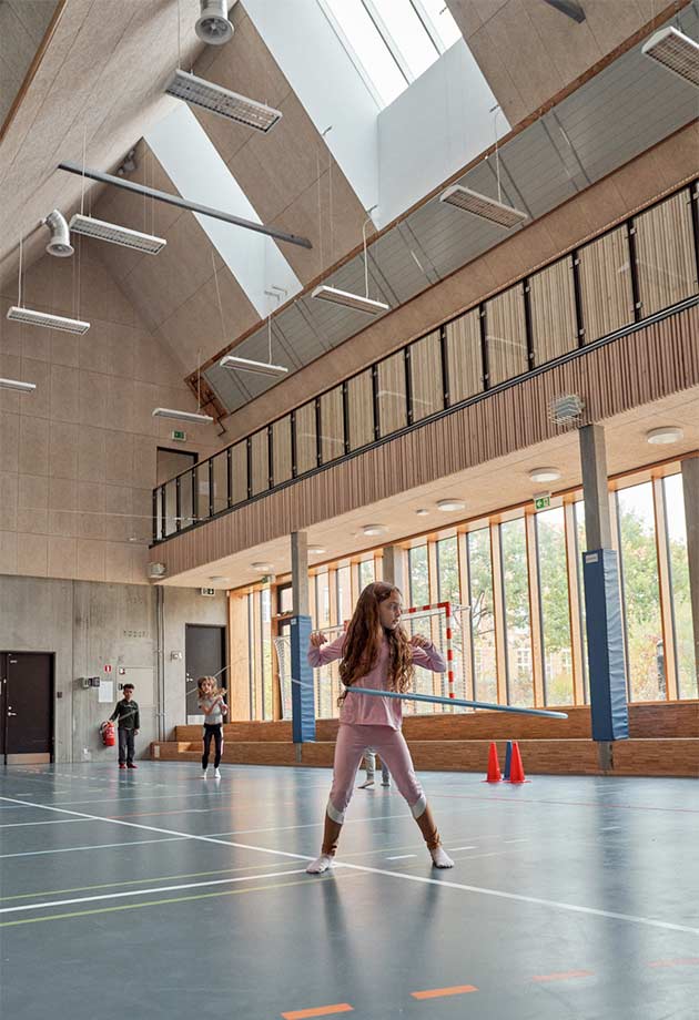 Flicka som leker i sporthall under VELUX takljusmoduler – Nordljus