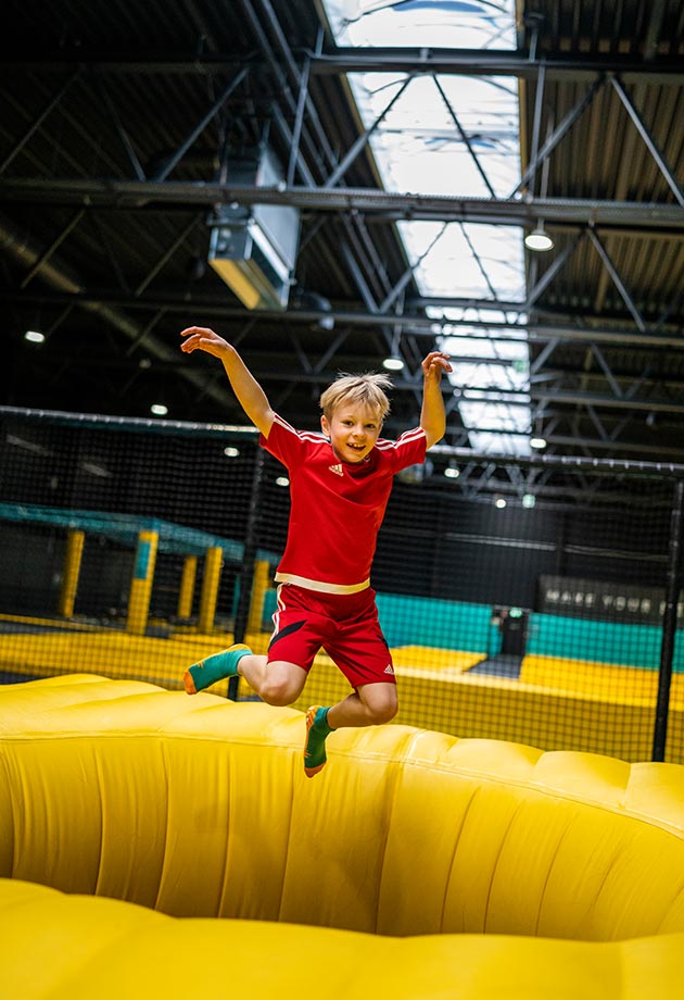 Enfant sautant dans une salle de trampoline avec lanterneau continu en polycarbonate.