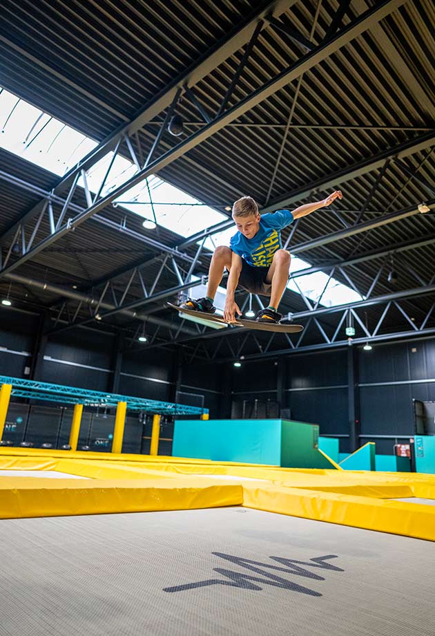 Kid with board jumping under a continuous rooflight